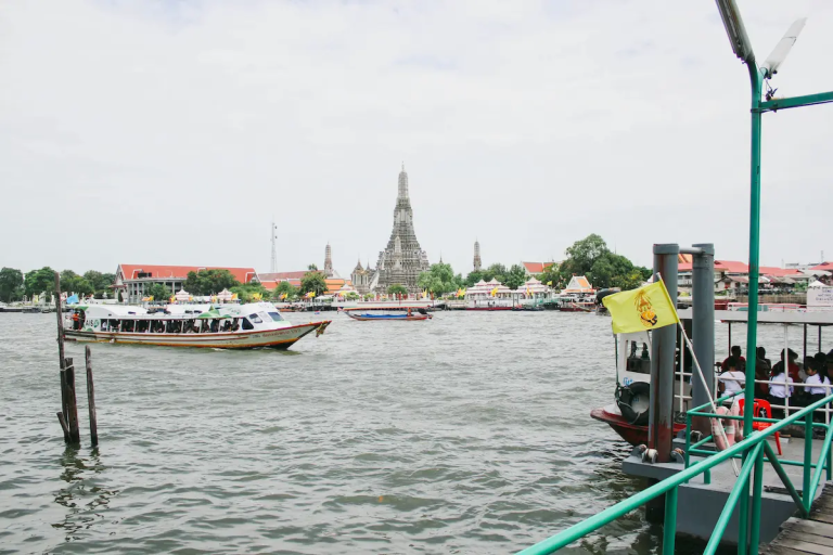 Bangkok first-time itinerary featured image showing Wat Arun across the Chao Phraya River from a pier with boats and city movement