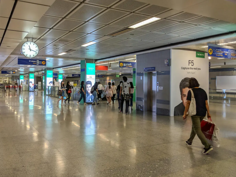 Thailand itinerary planning concept showing a Bangkok MRT station concourse with travelers, signage, and movement during a travel day