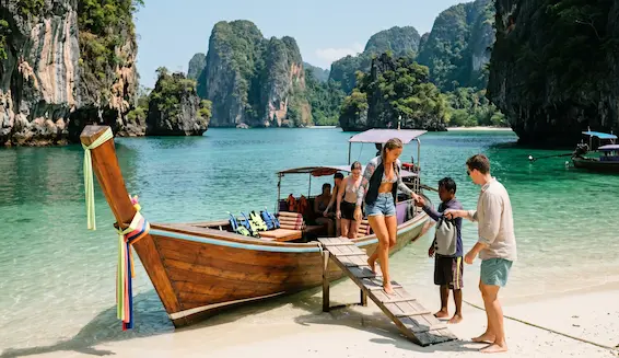 Travellers arriving by longtail boat at tropical island beach near Phuket for an active holiday package