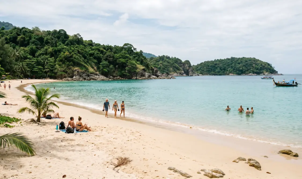 Scenic Phuket beach bay with travellers relaxing, clear water, soft sand, tropical hills, and longtail boats for a free Phuket travel guide