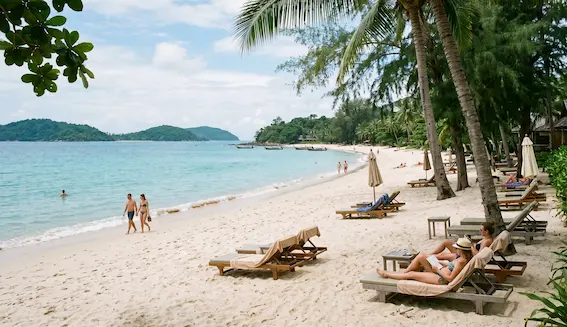 Relaxed Phuket beach scene with loungers, palm trees and calm shoreline for a Phuket holiday package