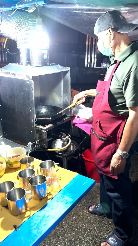 Street food vendor cooking Kai Jeow in a wok at a food stall in Phuket Thailand