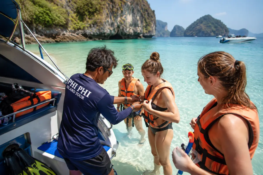 Guide Assisting Guests During the Tour guide assisting guests in shallow water during a snorkelling stop on the Simba Phi Phi Sunrise Tour in Phi Phi Islands.