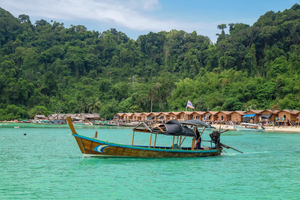 Traditional longtail boat and national park accommodation on the Surin Islands Thailand surrounded by tropical rainforest